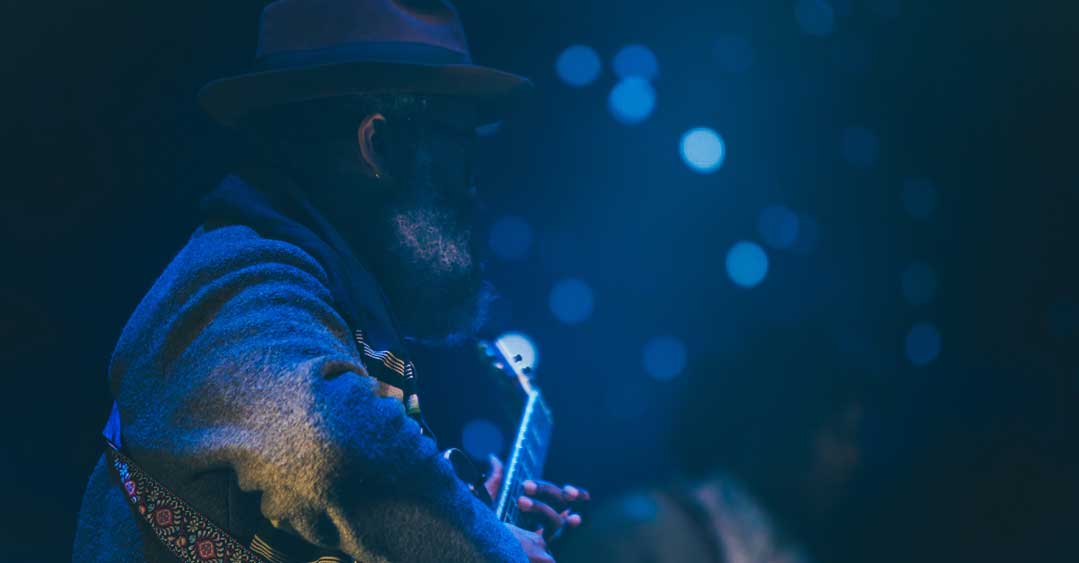 A guitarist playing under blue stage lighting