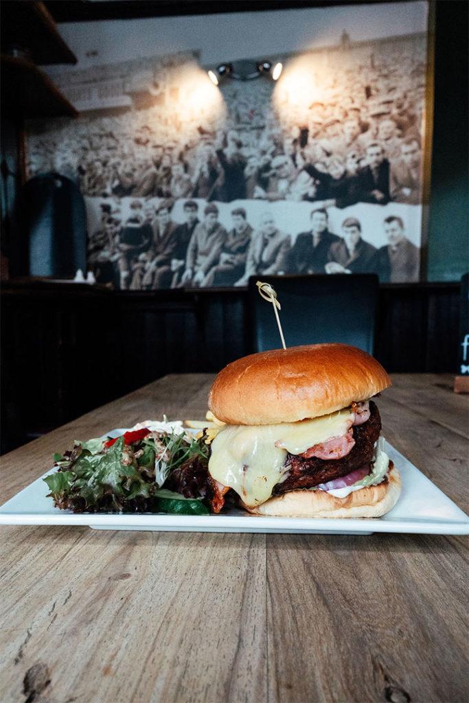 A homemade burger with melted cheese and bacon on a plate
