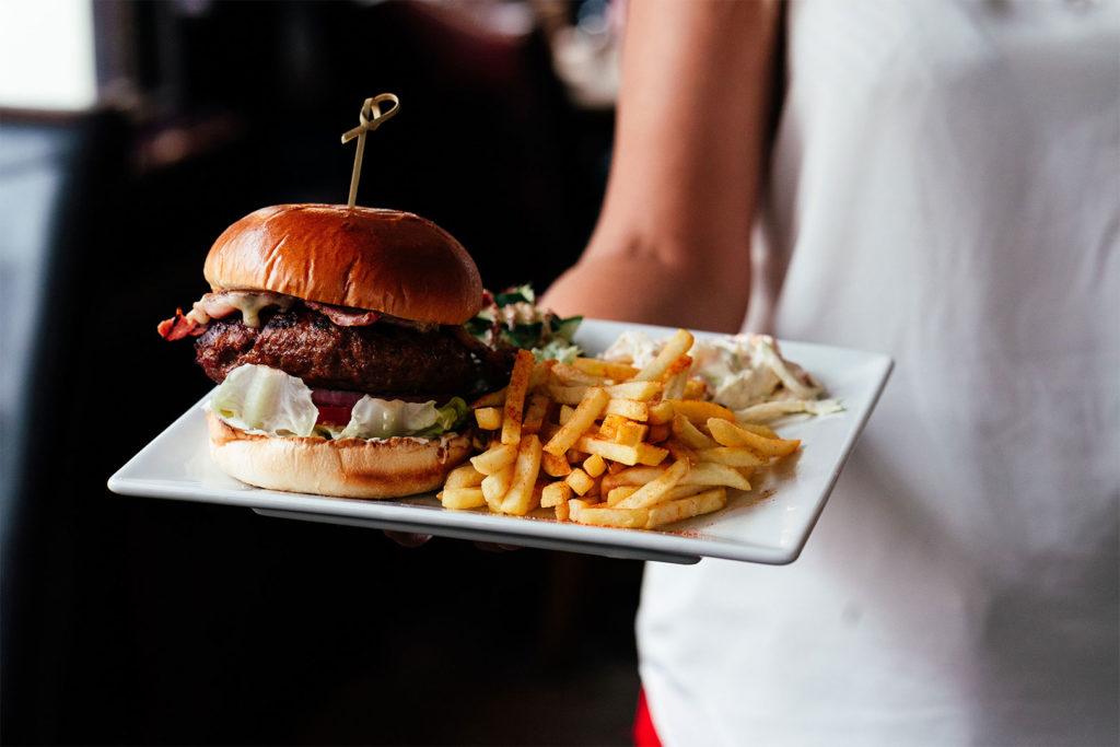 A burger and fries being carried to a table