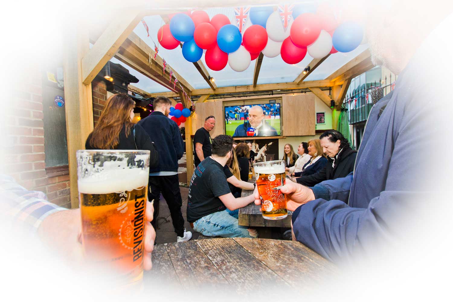 Drinkers watching football under the covered patio at the rear of the pub