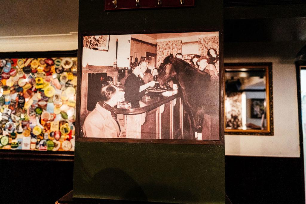 A historic framed photograph and a wall of vintage beer mats inside the pub