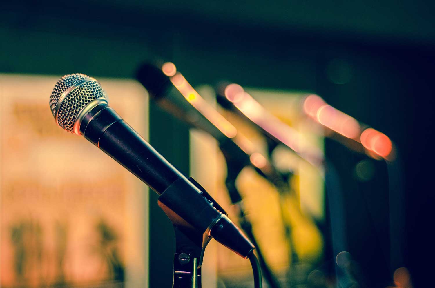 A microphone on a stand lit by stage lights