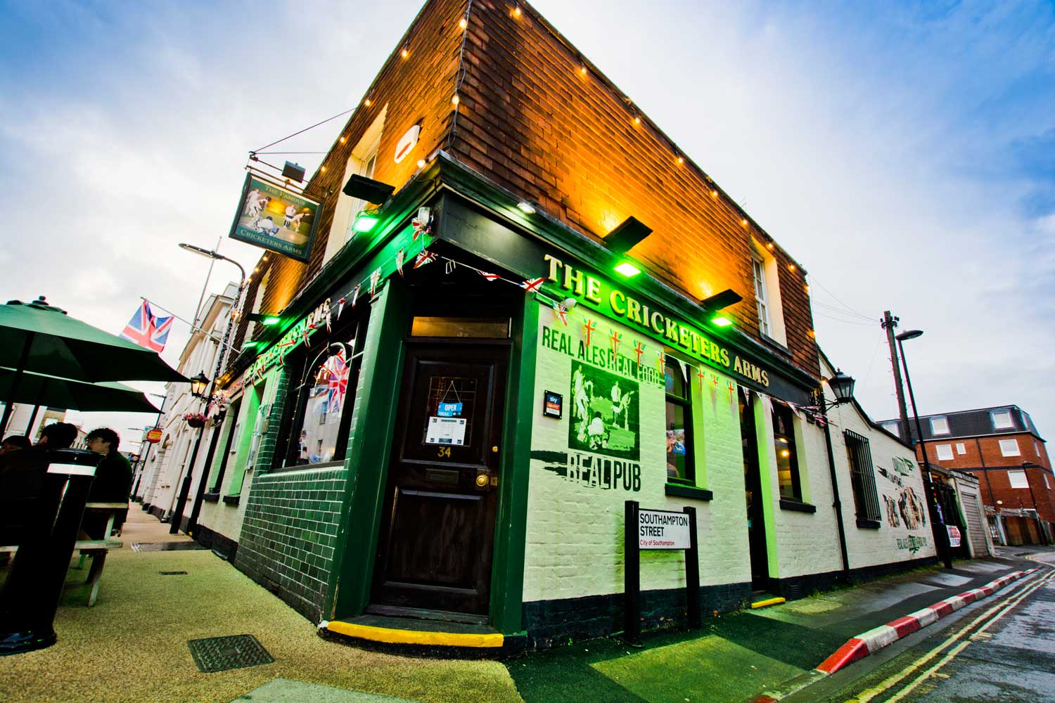 The Cricketers Arms on the corner of Carlton Place, Southampton, lit up green and gold at dusk