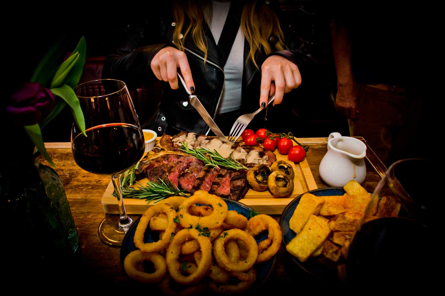 A guest cutting into a sharing steak board in the pub