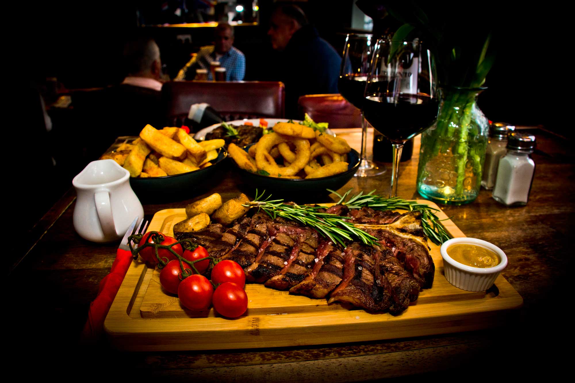 A sharing steak board with chips and onion rings on a pub table